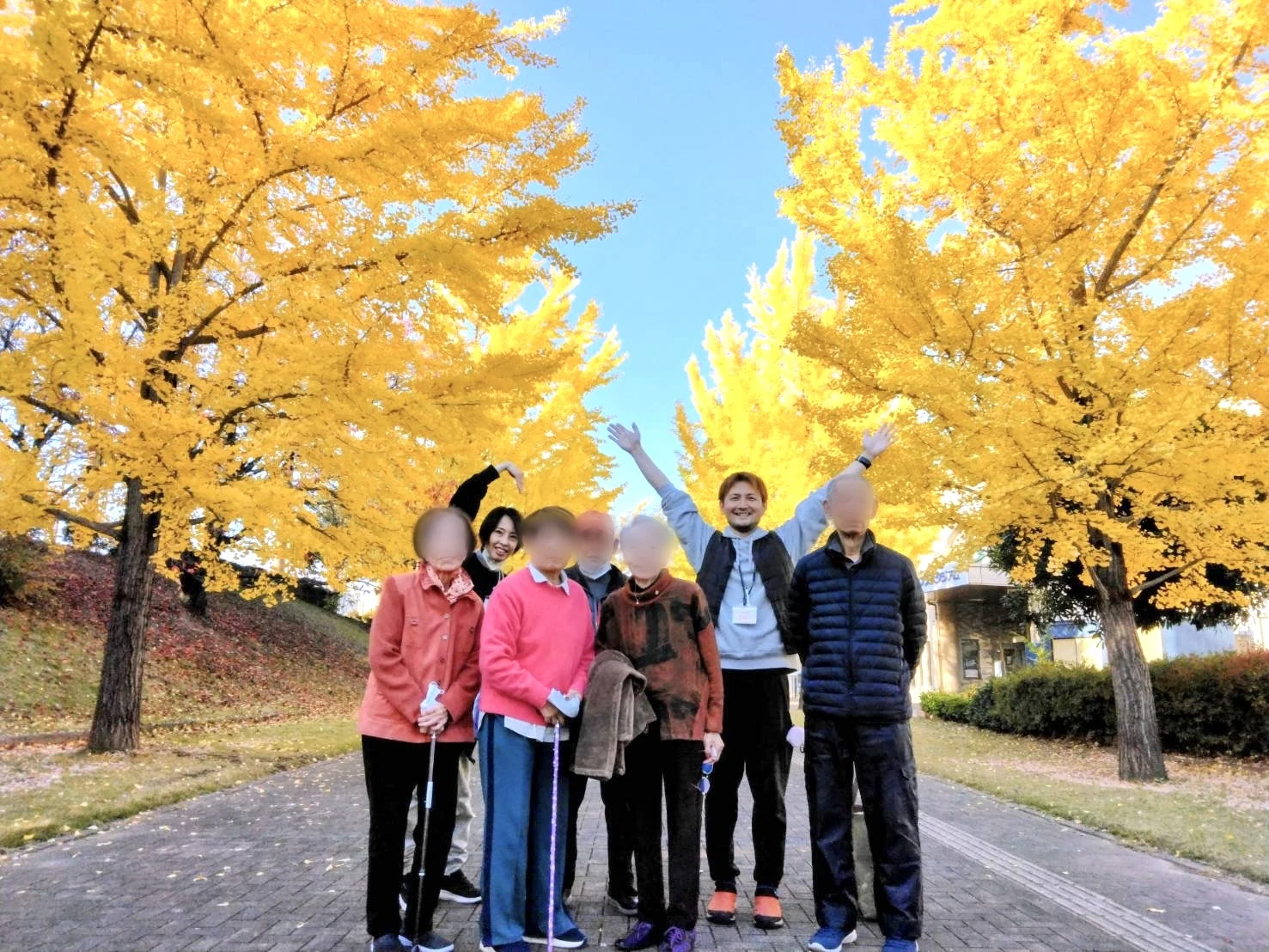 イチョウ並木の下で利用者さんとスタッフが集まるゆたかの屋外活動写真